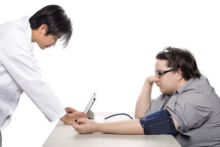 Female patient getting checkup with a doctor using a modern electronic blood pressure monitor. The device is a smart medical gadget and connects to a tablet.  The diagnosis is made possible by health insurance.の写真素材