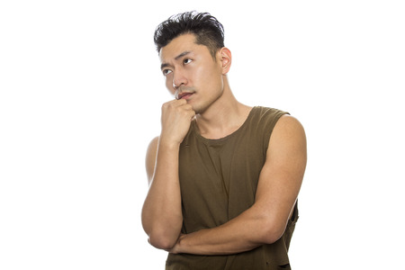 Athletic Asian male with trendy torn sleeveless shirt on a white background.  He is displaying confused or thinking expressions or gestures.  The handsome chinese or japanese man is muscular and physically fitの写真素材