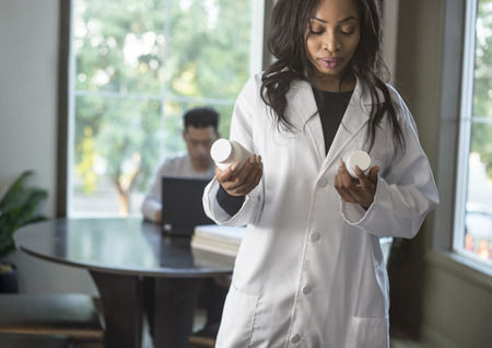 Female scientist in a lab coat researching with her male coed med school student in a campus laboratory.  The woman is learning science and technology in medical industry. の写真素材