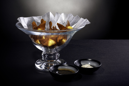 Deep fried cheese wontons or crab rangoons in a bowl.  This appetizer is made with seafood and wrap.  The dish is tasty and delicious but greasy and fatty.  The image depicts asian food.の写真素材