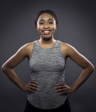 Black fitness trainer or athlete posing as a gritty woman on a dark background.  She is fit and slim.  The image depicts female sports and health.の写真素材