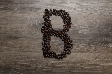 Dark roasted coffee bean arranged on a wooden table in the shape of text alphabet letter Bの写真素材