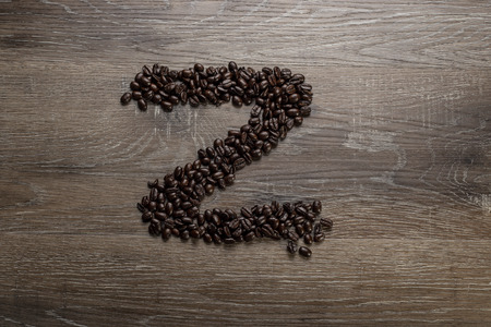 Dark roasted coffee bean arranged on a wooden table in the shape of text alphabet letter Zの写真素材