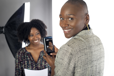 Black female actress doing a self tape audition via cell phone camera in a studio while reading to a casting director.  Depicts the Hollywood entertainment industry process.の写真素材