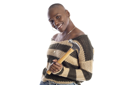 Black African American female model holding a hammer repair tool looking independent and self reliant.  She is depicting home improvement and woman individualism. の写真素材
