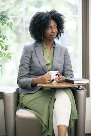 Black African American female as an adult student drinkling coffee before reading a book to study.  The intelligent woman can also be a teacher getting ready in the morning.の写真素材