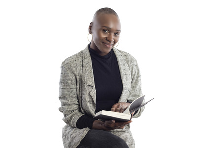 Black African American female author sitting with a book like she is about to be a keynote speaker on a seminar.  She looks like a business woman or a journalist. の写真素材