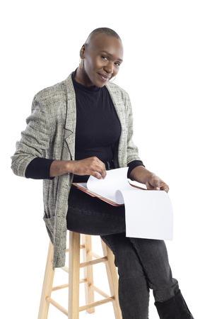 Black African American businesswoman reading contracts or reports or a teacher preparing her lessons for a class or seminar.  She is sitting and isolated on a white background with paperwork.の写真素材