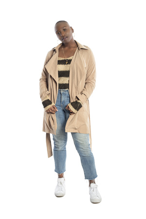 Confident black African American female model wearing Fall or Spring style fashion with a jacket or coat and jeans.  She has a bald hairstyle and isolated on a white background.の写真素材