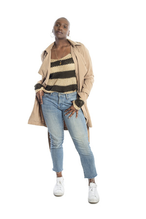 Confident black African American female model wearing Fall or Spring style fashion with a jacket or coat and jeans.  She has a bald hairstyle and isolated on a white background.の写真素材