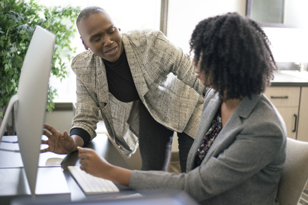 Black African American businesswomen or coworkers together in an office doing teamwork or job training.  The women are working together at a startup business.の写真素材