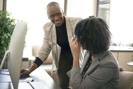 Black African American businesswomen or coworkers together in an office doing teamwork or job training.  The women are working together at a startup business.の写真素材