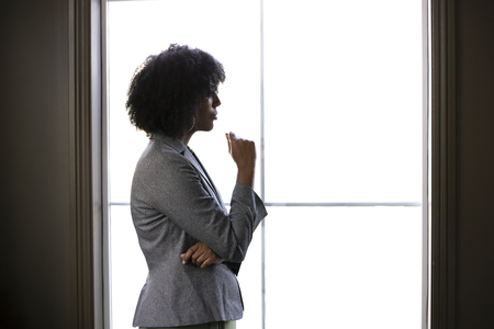 Silhouette of a stressed out black African American businesswoman looking worried and thinking about...