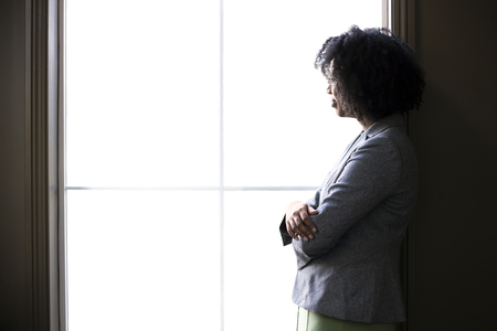 Silhouette of a black African American businesswoman thinking by the office window. She is brainstorming or planning for her startup business. の写真素材