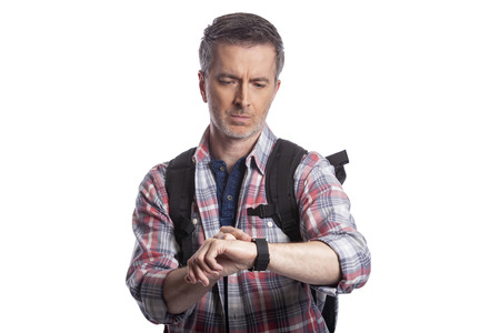 Middle-aged man or senior citizen checking heart rate pulse with health apps on a smartwatch.  He also looks like a hiker checking the wearable technology for gps navigation.の写真素材