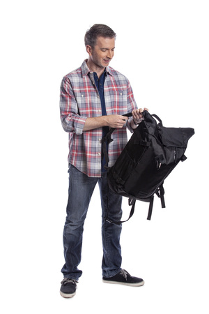 Middle-Aged man preparing a backpack for hiking or trekking.  He could also be a tourist packing hand carry luggage in preparation for a journey.の写真素材