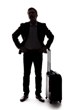 Silhouette of a businessman going on a business trip and traveling with luggage.  The man is carrying bags like preparing to board a flight at an airport. の写真素材
