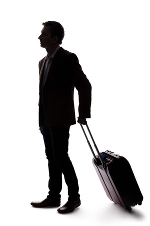 Silhouette of a businessman going on a business trip and traveling with luggage.  The man is carrying bags like preparing to board a flight at an airport. の写真素材