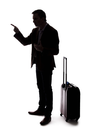 Silhouette of an angry businessman or traveler with luggage as if arguing at an airport about delays or cancellations.  The tourist is angry about the stress of travel. の写真素材