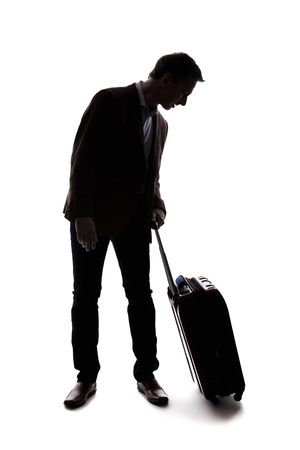 Silhouette of a businessman going on a business trip and traveling with luggage.  The man is carrying bags like preparing to board a flight at an airport. の写真素材
