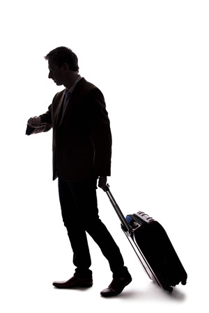 Silhouette of a businessman going on a business trip and traveling with luggage.  The man is carrying bags like preparing to board a flight at an airport. の写真素材