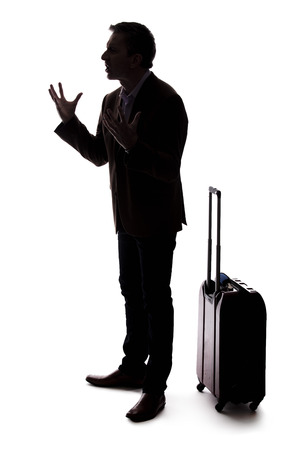 Silhouette of an angry businessman or traveler with luggage as if arguing at an airport about delays or cancellations.  The tourist is angry about the stress of travel. の写真素材
