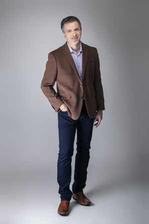 Bearded middle aged fashion model posing with business casual style outfit for mature and confident look.  The trendy brown jacket and jeans and facial hair shows an elegant apparel.の写真素材