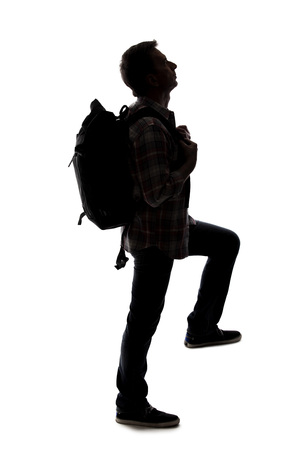 Silhouette of a hiker or mountain climber reaching to move up an imaginary mountain. The image depicts gestures or shape of an active man exploring.の写真素材