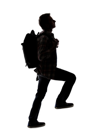 Silhouette of a hiker or mountain climber reaching to move up an imaginary mountain. The image depicts gestures or shape of an active man exploring.の写真素材