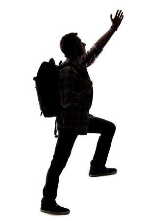 Silhouette of a hiker or mountain climber reaching to move up an imaginary mountain. The image depicts gestures or shape of an active man exploring.の写真素材