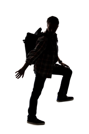 Silhouette of a hiker or mountain climber reaching to move up an imaginary mountain. The image depicts gestures or shape of an active man exploring.の写真素材