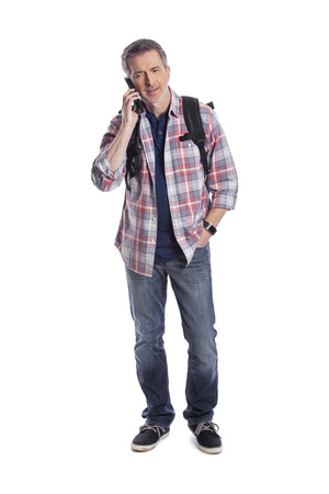 Male tourist or a hiker using a cellphone to call or message a rideshare so he can travel.  The man is wearing a backpack and using a smart phone.  Isolated on a white background.の写真素材
