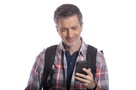 Male tourist or a hiker using a cellphone to call or message a rideshare so he can travel.  The man is wearing a backpack and using a smart phone.  Isolated on a white background.の写真素材