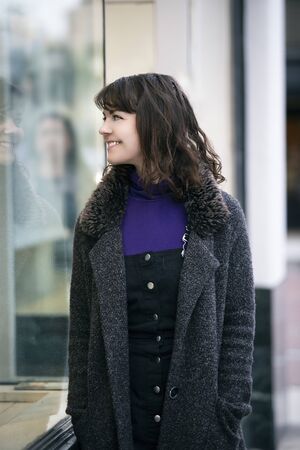 Woman walking outdoors in a city. She is window shopping and looking at a store sale advertising or marketing apparel and clothing on a display glass. の写真素材