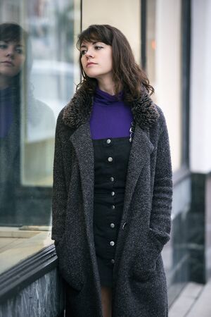 Woman walking outdoors in a city. She is window shopping and looking at a store sale advertising or marketing apparel and clothing on a display glass. の写真素材