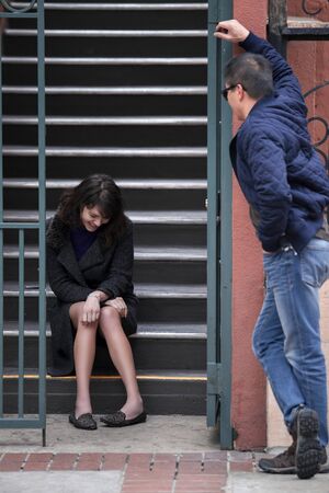 Male flirting with female neighbor sitting on the stairs outside of an apartment complex or condo.  He is confident and charismatic talking to her and depicts dating and relationships.の写真素材