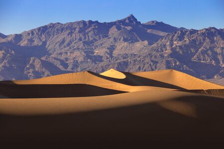 Sand dunes in a desert landscape in Death Valley California.  The vast barren land is dry and arid due to droughts result of global warming and climate change.の写真素材