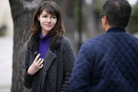 Female pedestrian walking into a friend by coincidence on the street.  They are meeting and greeting each other outdoors in a city or a park. Two people looked surprised.の写真素材