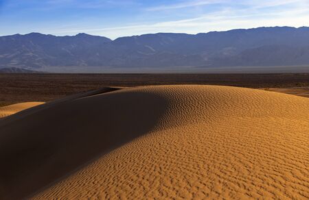 Sand dunes in a desert landscape in Death Valley California.  The vast barren land is dry and arid due to droughts result of global warming and climate change.の写真素材