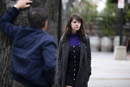 Man being rude, leering and cat calling or sexually harassing a woman walking on the street.  Also depicts crime and safety with a stalker following a female victim.の写真素材