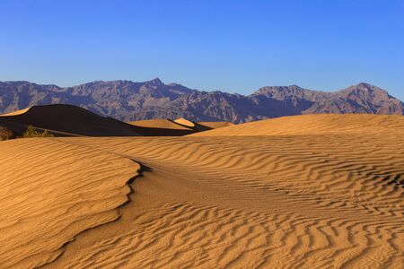Sand dunes in a desert landscape in Death Valley California.  The vast barren land is dry and arid due to droughts result of global warming and climate change.の写真素材