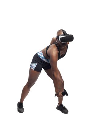 Athletic black female gamer wearing a vr headset and exercising in a virtual reality gym for weight loss.  The image depicts technology used in sports and esports entertainment for healthy lifestyle.の写真素材