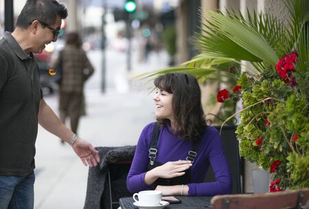 Woman taking a break in an outdoor coffee shop or local cafe in the city and waiting to meet a friend.  She is sitting down in a sidewalk restaurant hanging out. Depicts local business.の写真素材