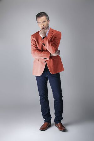 Middle-aged fashion model wearing coral colored sports coat or jacket for the fall clothing collection.  Depicts modern colorful apparel style for 2019.の写真素材