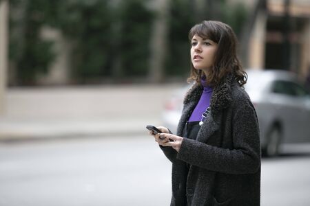 Young female using mobile phone app and waiting for a rideshare or pedestrian tourist checking online map for gps navigation.  Depicts city life and how millennials travel.の写真素材