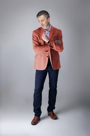 Middle-aged fashion model wearing coral colored sports coat or jacket for the fall clothing collection.  Depicts modern colorful apparel style for 2019.の写真素材