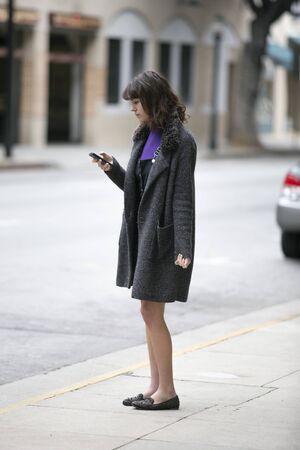 Young female using mobile phone app and waiting for a rideshare or pedestrian tourist checking online map for gps navigation.  Depicts city life and how millennials travel.の写真素材
