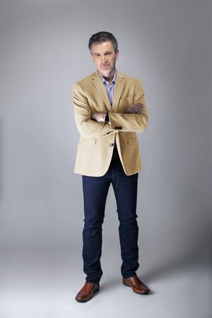 Middle-aged Caucasian businessman looking posh wearing modern fall collection style beige jacket.  Depicts confident and mature stylish fashion.  Shot in studio for catalog look.の写真素材