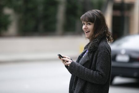 Young female using mobile phone app and waiting for a rideshare or pedestrian tourist checking online map for gps navigation.  Depicts city life and how millennials travel.の写真素材