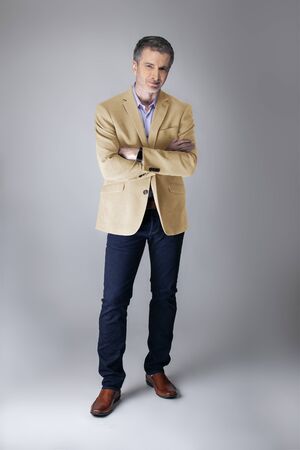 Middle-aged Caucasian businessman looking posh wearing modern fall collection style beige jacket.  Depicts confident and mature stylish fashion.  Shot in studio for catalog look.の写真素材
